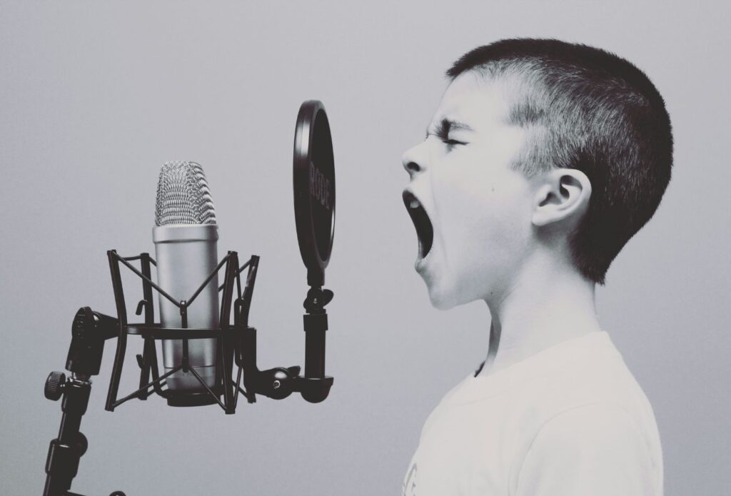 shows a boy speaking in front of a microphone