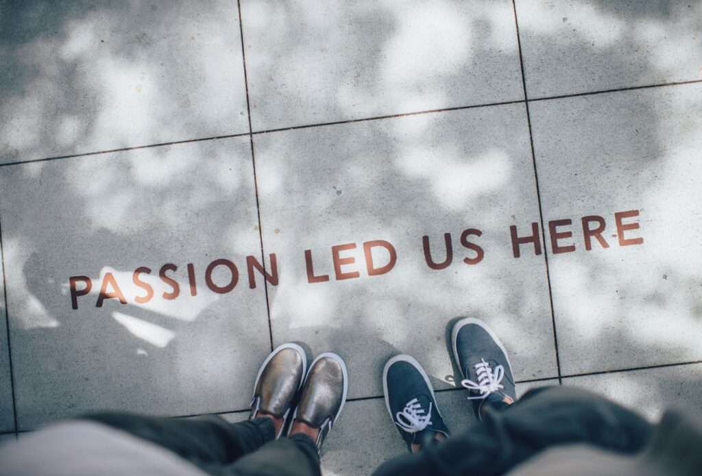 shows people standing next to the sign 'PASSION LED US HERE' - How to Create Brand Tone of Voice Guidelines