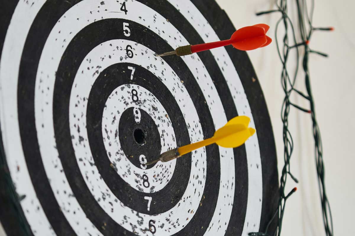 Depicts a dartboard with colourful darts