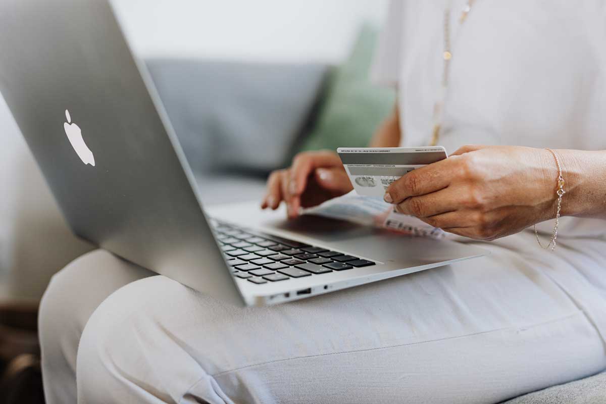 Shows a man online shopping with a laptop