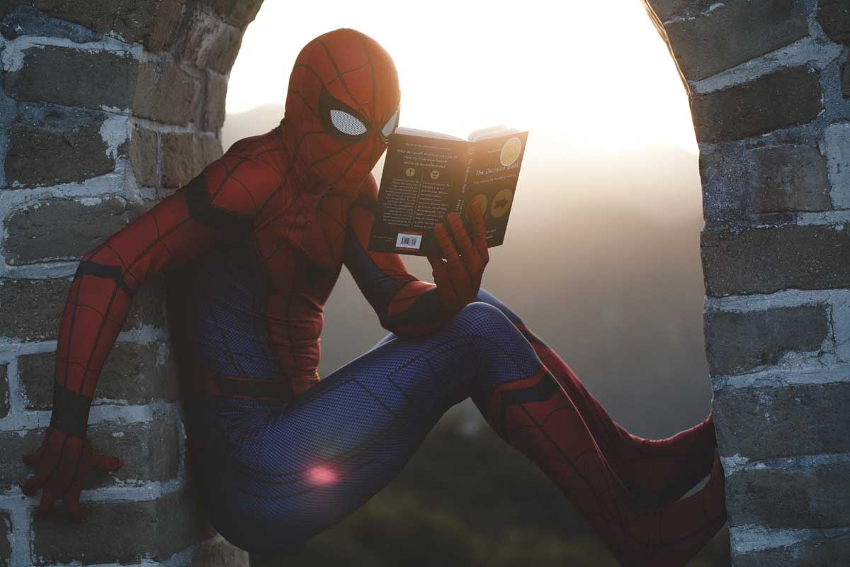 Shows a man dressed as Spiderman reading a book - How to write a business report
