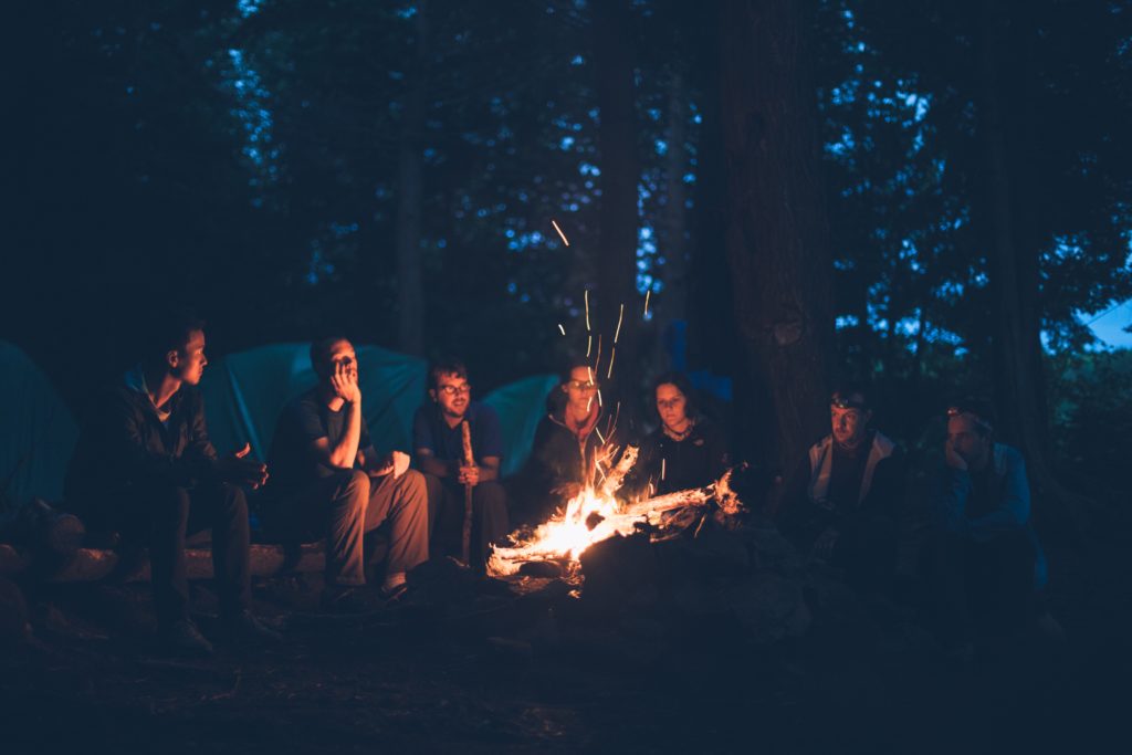 Shows people sitting by a campfire telling a story