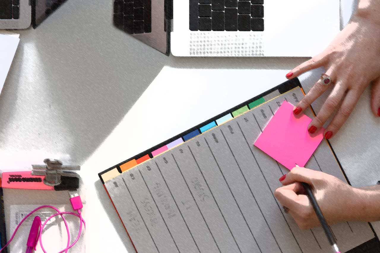 Shows a woman writing on a post-it note