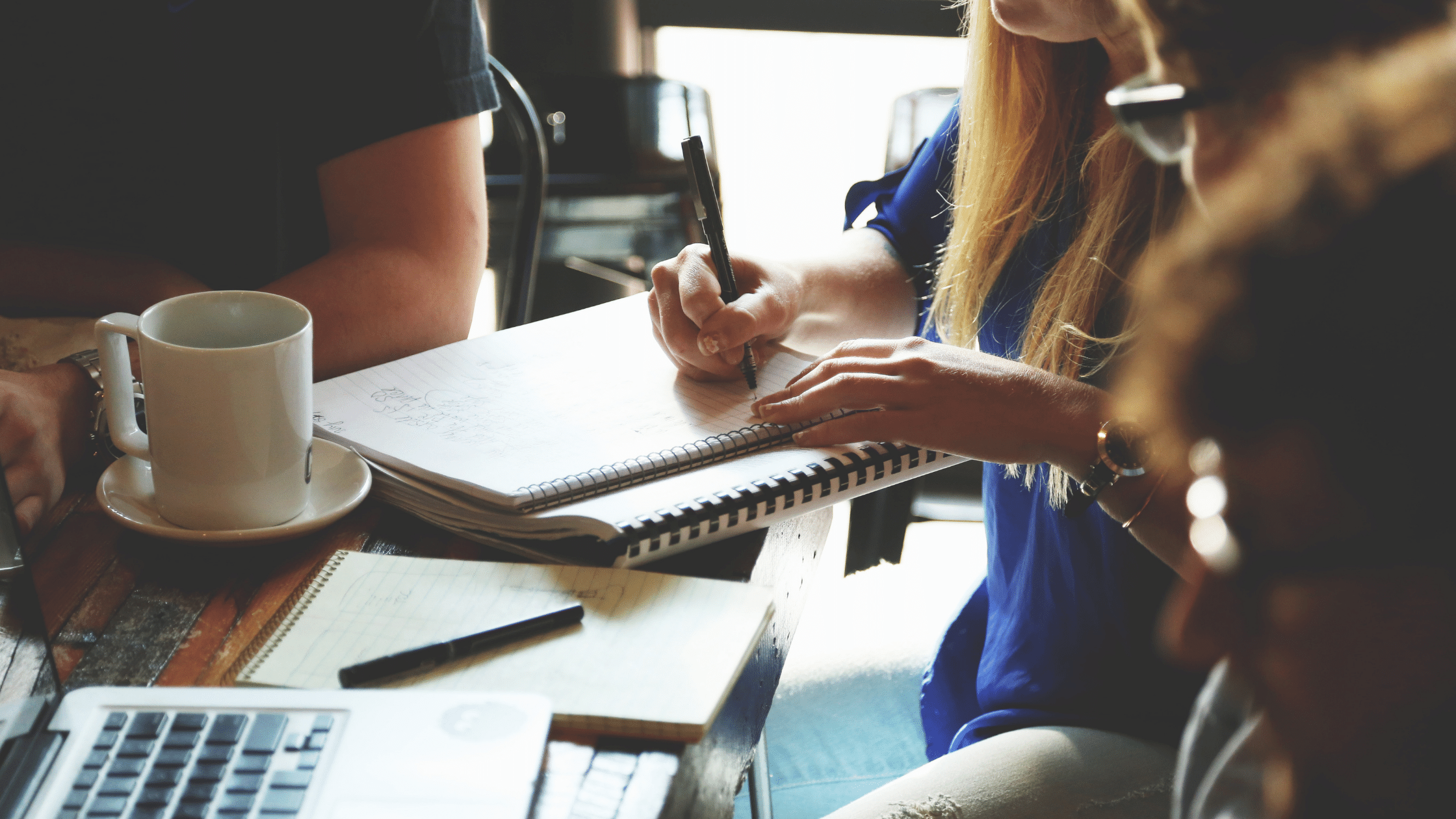 A woman writing on a notepad at her desk