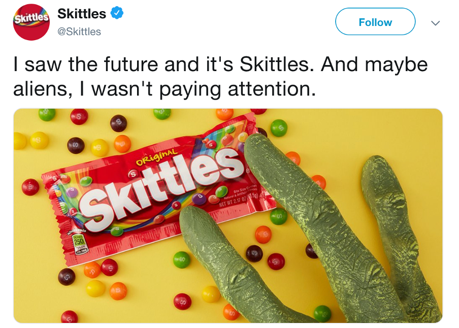 Shows an alien hand touches a bag of Skittles sweets