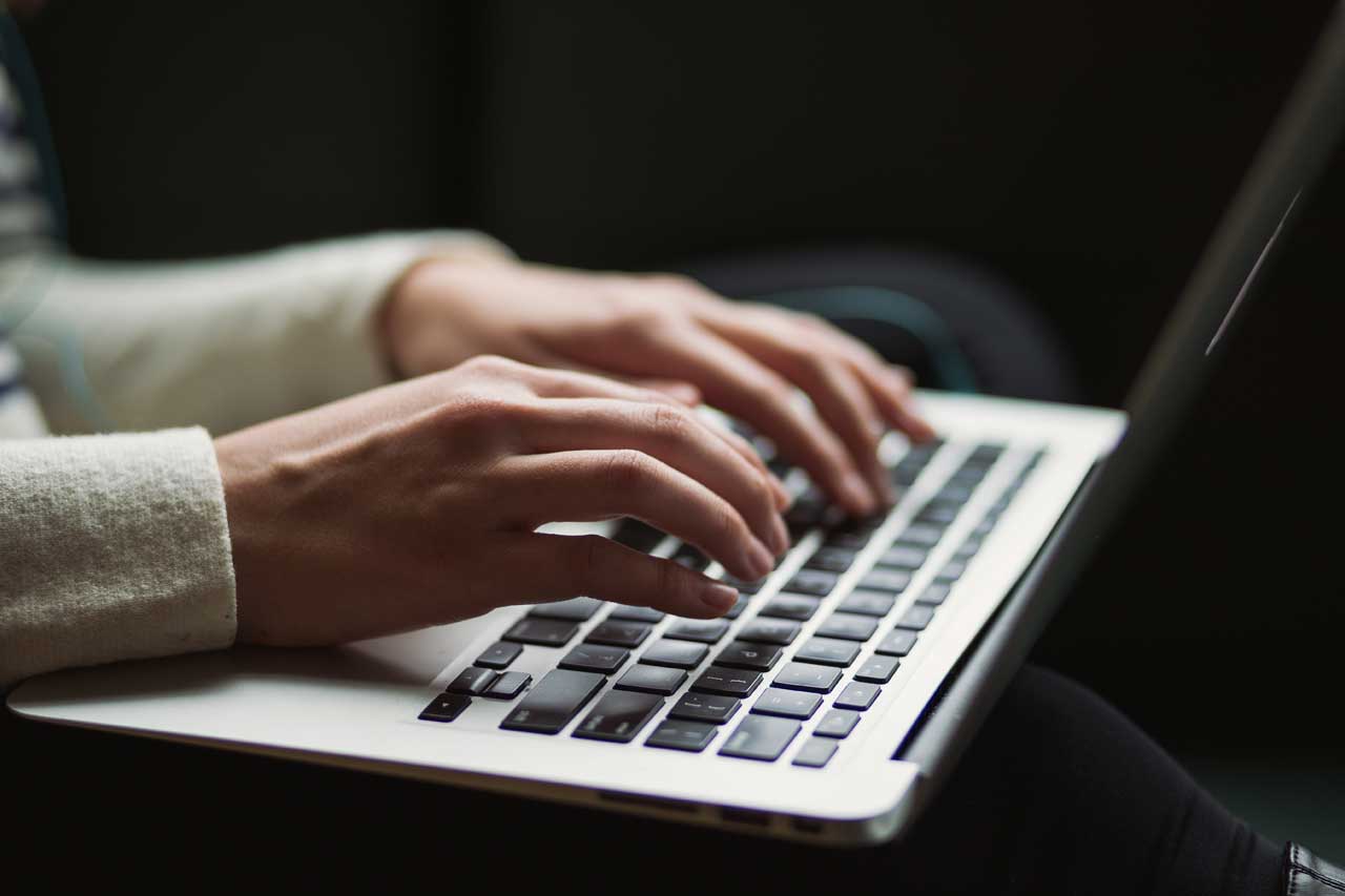Report writing service - Shows a person typing on a laptop