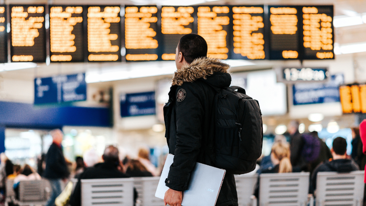 shows an image of a man looking at the departure boards