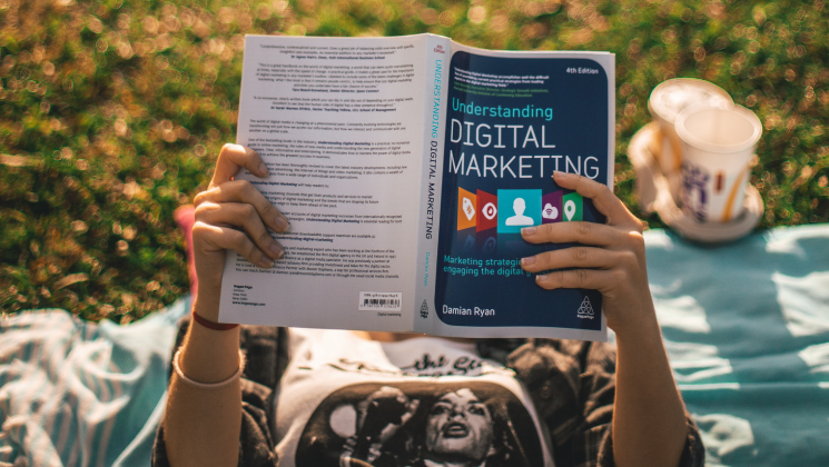 shows an image of a woman lying on the grass reading a book - content marketing guide
