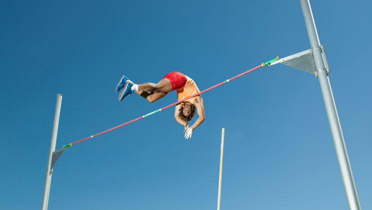 shows a person jumping over a pole 