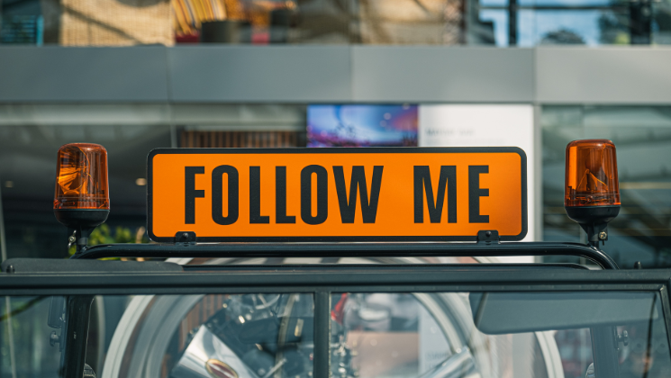 shows an image of a sign that says 'FOLLOW ME' in orange capitals