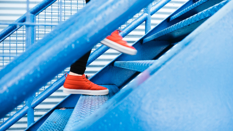 shows an image of someone wearing red trainers walking up blue stairs