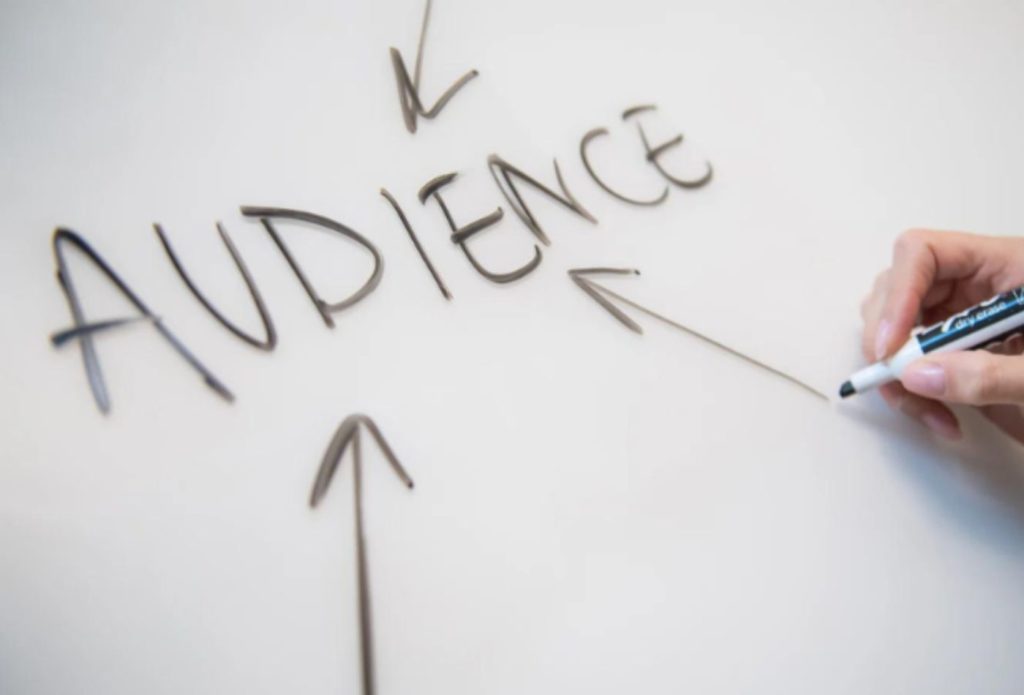 shows the word 'AUDIENCE' on a white board