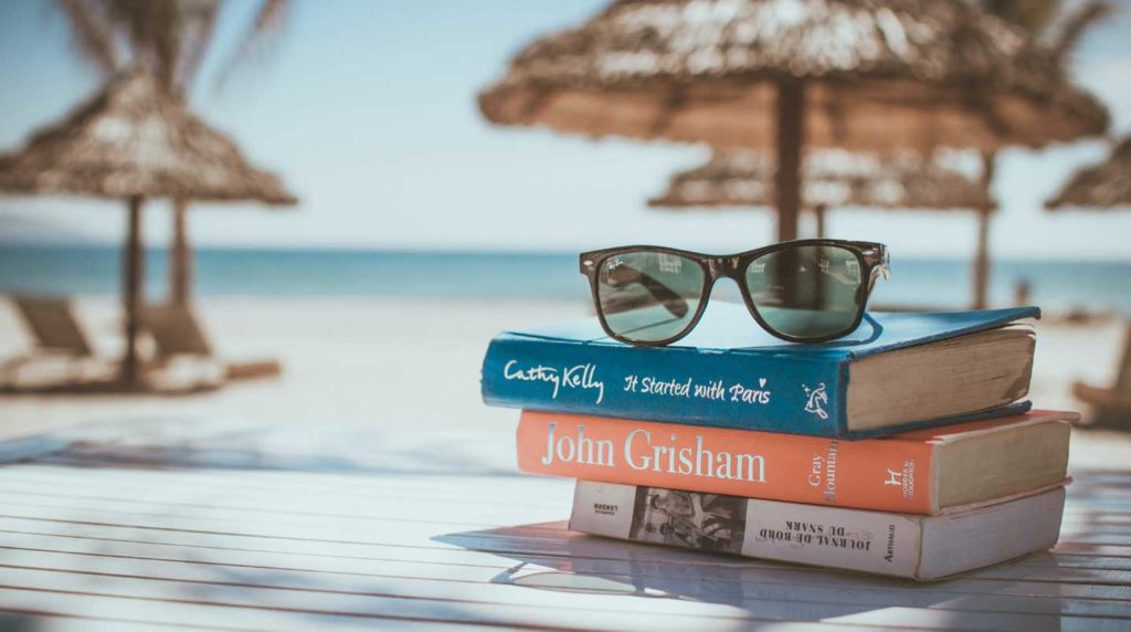 Travel article examples - Shows a stack of books on a beach