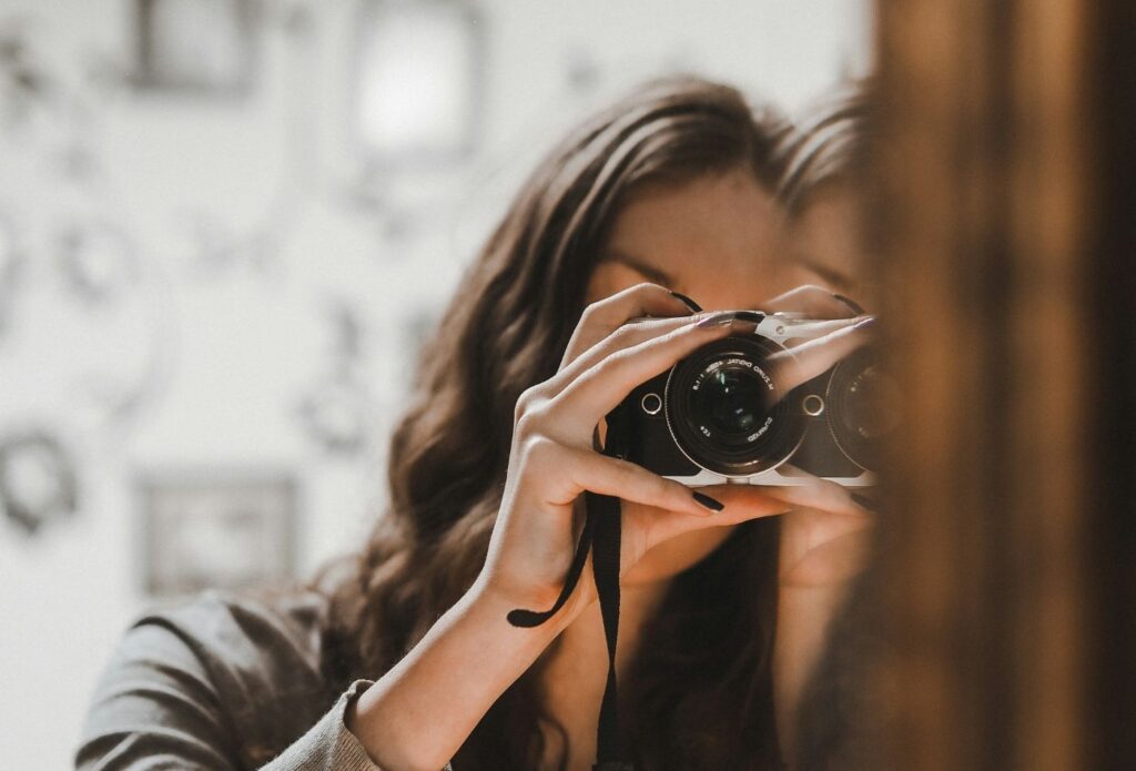 shows a woman taking pictures on a  camera - Clothing store description examples