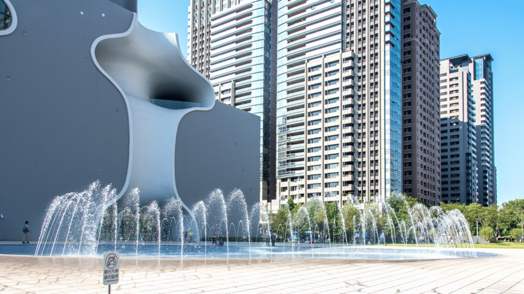 shows a fountain next to a tall building