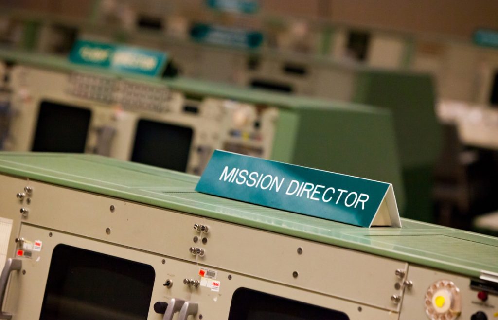 Shows a mission control console with 'Mission Director' in written text
